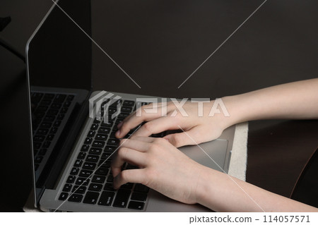 Close-up shot of a teenager's hands hovering over a laptop keyboard, showcasing computer literacy and modern technology skills. 114057571