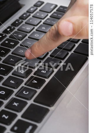 A teenager's finger above the laptop keyboard in close-up. Computer literacy 114057578