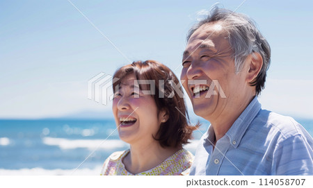 Japanese senior couple smiling on the beach Japanese senior couple smiling on the beach 114058707