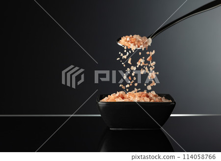 Pink Himalayan salt in a small black ceramic bowl. 114058766