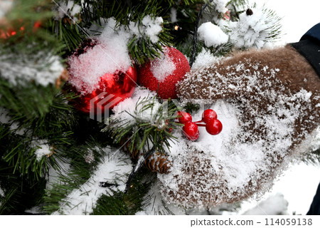 Red Christmas balls hanging on a fir branches covered by snow. New Year tree with decorations, magic of a holiday 114059138