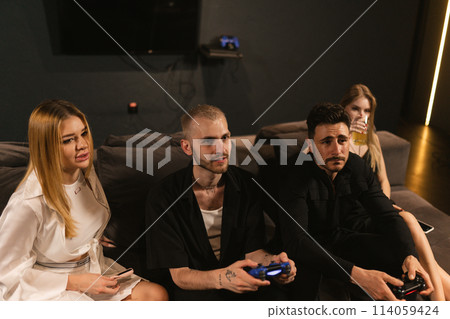 Lady drinks cocktail enjoying video game competition of men Lady drinks cocktail enjoying video game competition of men 114059424
