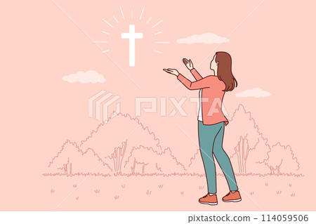 Catholic woman looks at cross glowing in sky, praying to god for help in finding right path 114059506