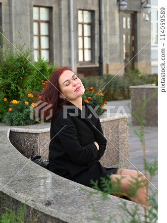 a confident young attractive woman in a black dress and high-heeled shoes walks through the streets of the city, the woman smiles and enjoys life a confident young attractive woman in a black dress and high-heeled shoes walks through the streets of the city, the woman smiles and enjoys life 114059589