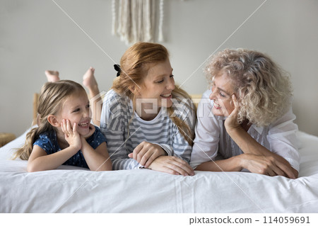 Girl lying on bed with young mother and loving granny Girl lying on bed with young mother and loving granny 114059691