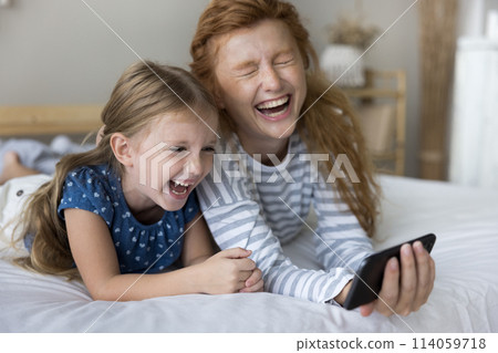 Laughing young mother watch funny video with daughter on smartphone Laughing young mother watch funny video with daughter on smartphone 114059718