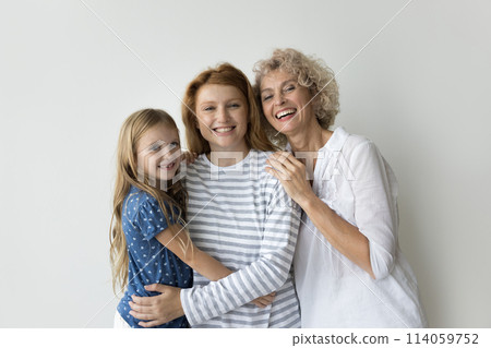 Beautiful multi-generational relatives women hugging posing on gray studio background Beautiful multi-generational relatives women hugging posing on gray studio background 114059752