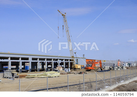Silhouettes of tower crane against a blue sky withe clouds. House under construction. Industrial skyline 114059794