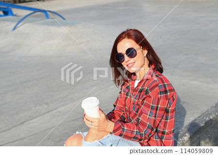 a confident young attractive woman in a black dress and high-heeled shoes walks through the streets of the city, the woman smiles and enjoys life 114059809