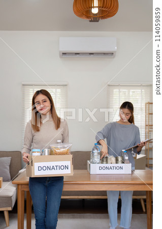 Donation and two woman volunteer asian of happy packing food in box at home. Charity Donation and two woman volunteer asian of happy packing food in box at home. Charity 114059859