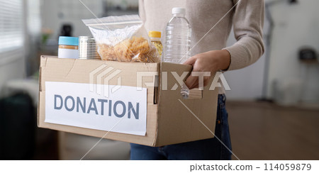 Woman volunteer holding food donation box at home Woman volunteer holding food donation box at home 114059879