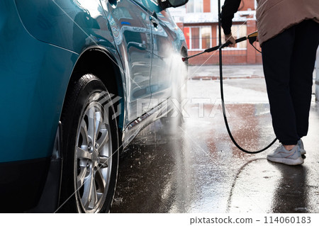 Woman washing her car in a self-service car wash station.Car wash self-service. Woman washing her car in a self-service car wash station.Car wash self-service. 114060183