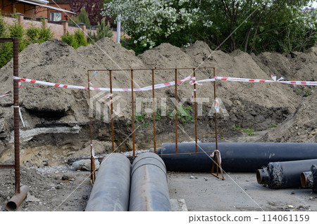 Laying of underground storm sewer pipes at a construction site. Installation of water supply and sanitary sewerage. Pipes of the groundwater drainage system Laying of underground storm sewer pipes at a construction site. Installation of water supply and sanitary sewerage. Pipes of the groundwater drainage system 114061159
