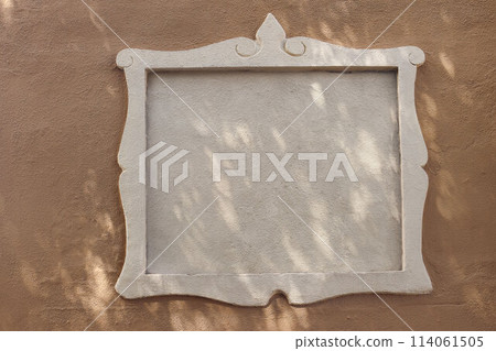 White street name sign, empty place for text, logo. Decorative architectural detail, frame or border. Old beige textured building, house wall in sunlight. Road sign. Mock up signboard. Copy space. 114061505