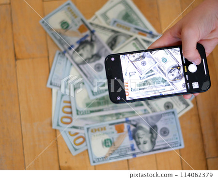 Smart Phone Extends Fanned 100 Dollar Bills 114062379