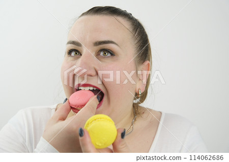 chubby fat woman quickly eats macaroons red lipstick on white background white clothes black manicure strawberry and lemon macarons dessert, gluttony diet calories chubby fat woman quickly eats macaroons red lipstick on white background white clothes black manicure strawberry and lemon macarons dessert, gluttony diet calories 114062686
