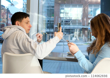 Two teenage friends taking a selfie, boy and girl, studio white background Two teenage friends taking a selfie, boy and girl, studio white background 114062698
