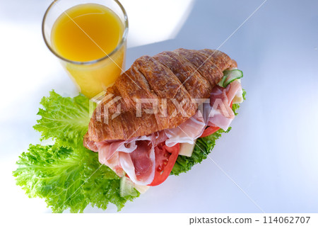croissant sandwich with meat jamon prosciutto with tomato Lettuce food rich pieces of cheese in breakfast France on a white plate expensive restaurant hotel getting a piece of meat with a fork croissant sandwich with meat jamon prosciutto with tomato Lettuce food rich pieces of cheese in breakfast France on a white plate expensive restaurant hotel getting a piece of meat with a fork 114062707