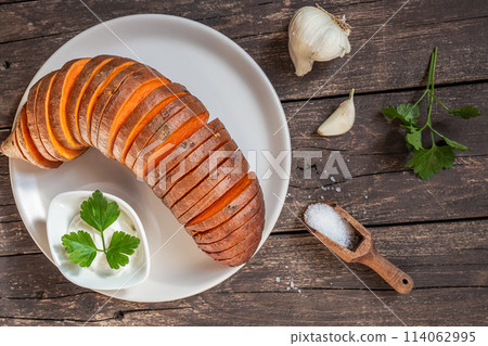 Roasted hasselback sweet potatoes with spices on a wooden table Roasted hasselback sweet potatoes with spices on a wooden table 114062995