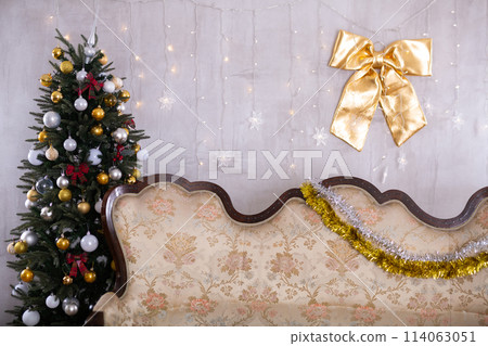 New Year Eve in room with a sofa and different gift boxes on it and big decorated Christmas tree next to it New Year Eve in room with a sofa and different gift boxes on it and big decorated Christmas tree next to it 114063051