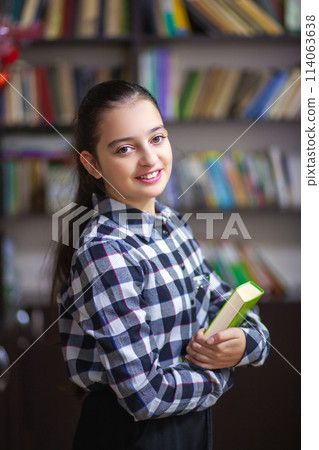 Beautiful schoolgirl reading a book in the library Beautiful schoolgirl reading a book in the library 114063638