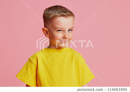 Portrait of little boy with sly expression looking at the camera against pink studio background. Cheating on lessons. Portrait of little boy with sly expression looking at the camera against pink studio background. Cheating on lessons. 114063999