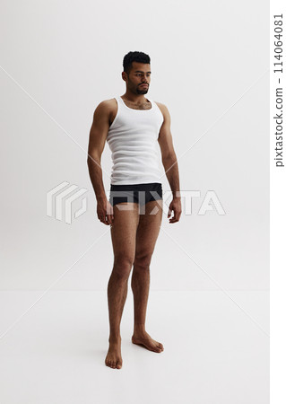 Full-length image of handsome African-American man standing shirtless in black boxes isolated on white background. Masculinity 114064081