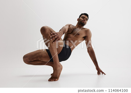 Contemplative pose of fit male model with focus on his physique indicating wellness isolated on white background 114064100
