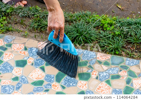A woman's hands cleaning with a broken blue broom - Eco-friendly, using tools carefully even if they break A woman's hands cleaning with a broken blue broom - Eco-friendly, using tools carefully even if they break 114064284