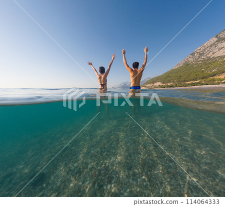 Sea summer landscape. Travel and Holiday concept. Happy young couple enjoying the sea. Back view under and above waterline 114064333