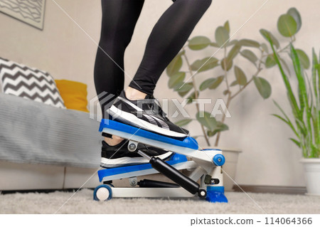 Home fitness, woman doing exercises on a stepper at home close up Home fitness, woman doing exercises on a stepper at home close up 114064366