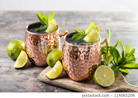Moscow mule cocktail served with ice and lime slice on wooden table. 114065206