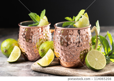 Moscow mule cocktail served with ice and lime slice on wooden table. 114065208