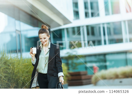 smiling modern woman worker near office building walking 114065326