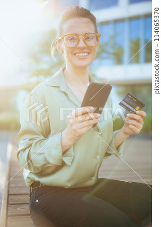happy business woman in green blouse and eyeglasses using phone 114065370