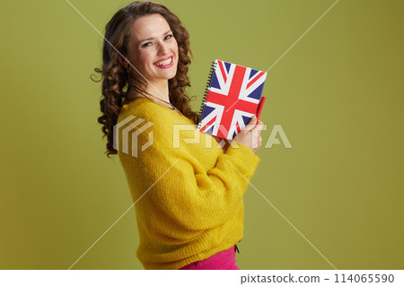 smiling fit female in yellow sweater on green background 114065590
