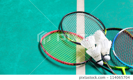 White badminton shuttlecocks and badminton rackets on green floor indoor badminton court White badminton shuttlecocks and badminton rackets on green floor indoor badminton court 114065704