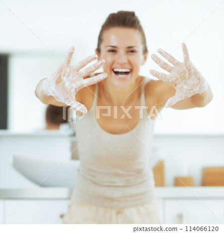 Happy young woman showing soapy hands 114066120