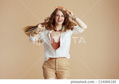 happy stylish woman in blouse and shorts jumping on beige happy stylish woman in blouse and shorts jumping on beige 114066180