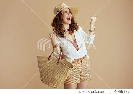 happy elegant woman in blouse and shorts rejoicing on beige happy elegant woman in blouse and shorts rejoicing on beige 114066182