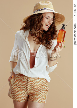 smiling trendy 40 years old woman in blouse and shorts on beige 114066184