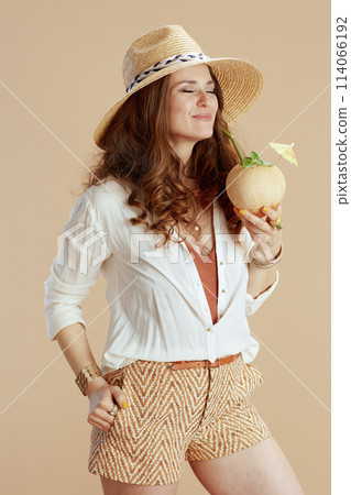 smiling stylish woman in blouse and shorts isolated on beige 114066192