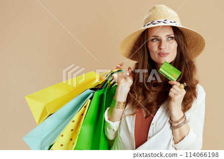 pensive housewife in blouse and shorts against beige 114066198