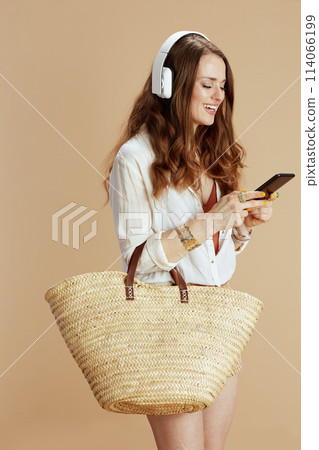 smiling trendy woman listening to music isolated on beige 114066199