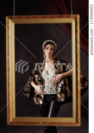 A woman in a Renaissance dress in a gold picture frame on a red background. A woman in a Renaissance dress in a gold picture frame on a red background. 114068003