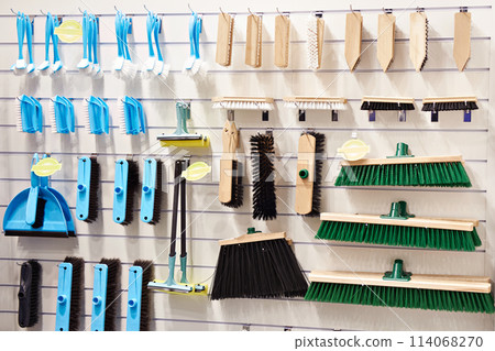 Plastic and wooden household brushes in hardware store 114068270