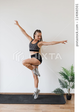Young woman practicing balance exercises in a bright room 114068501