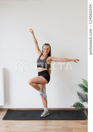 Young woman practicing balance exercises in a bright room 114068504