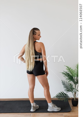 Fitness enthusiast standing on yoga mat in indoor setting Fitness enthusiast standing on yoga mat in indoor setting 114068507