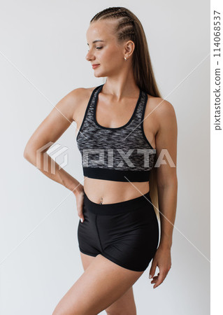 Fit young woman in athletic wear posing confidently 114068537